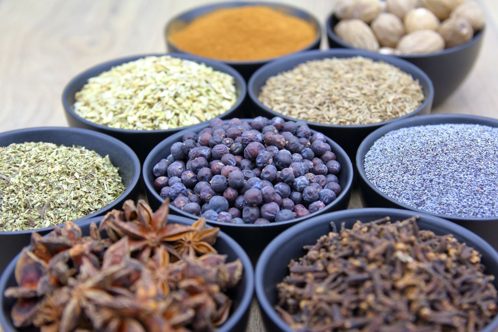 Bowls of whole spices and seeds including star anise and cloves