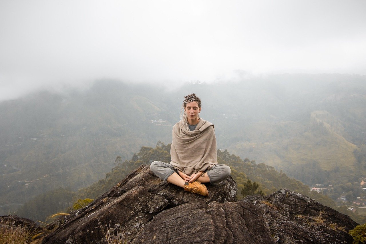 Zwei Menschen üben Yoga auf einer Terrasse mit Blick in die Natur Keralas
