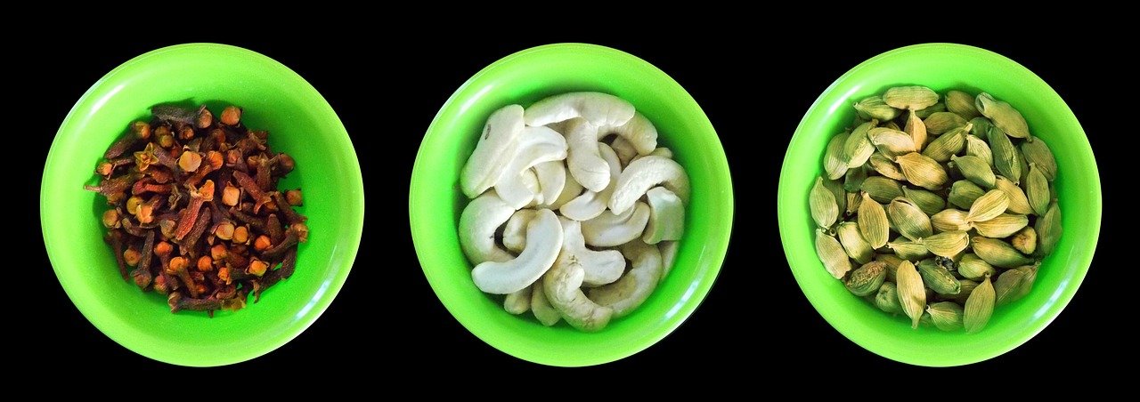 Verschiedene ayurvedische Gewürze in kleinen Schalen auf hellem Holzuntergrund