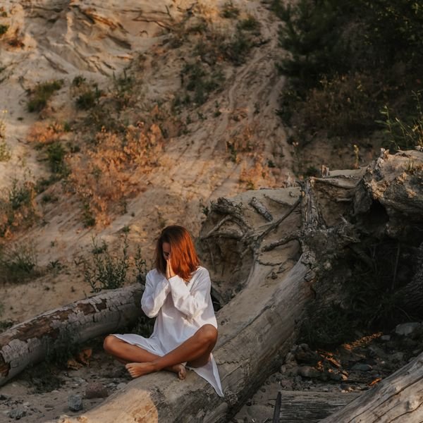 Woman meditating outdoors on a fallen tree trunk in nature