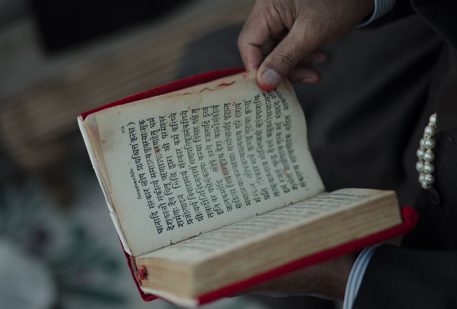 Hand holding an old book printed in Sanskrit