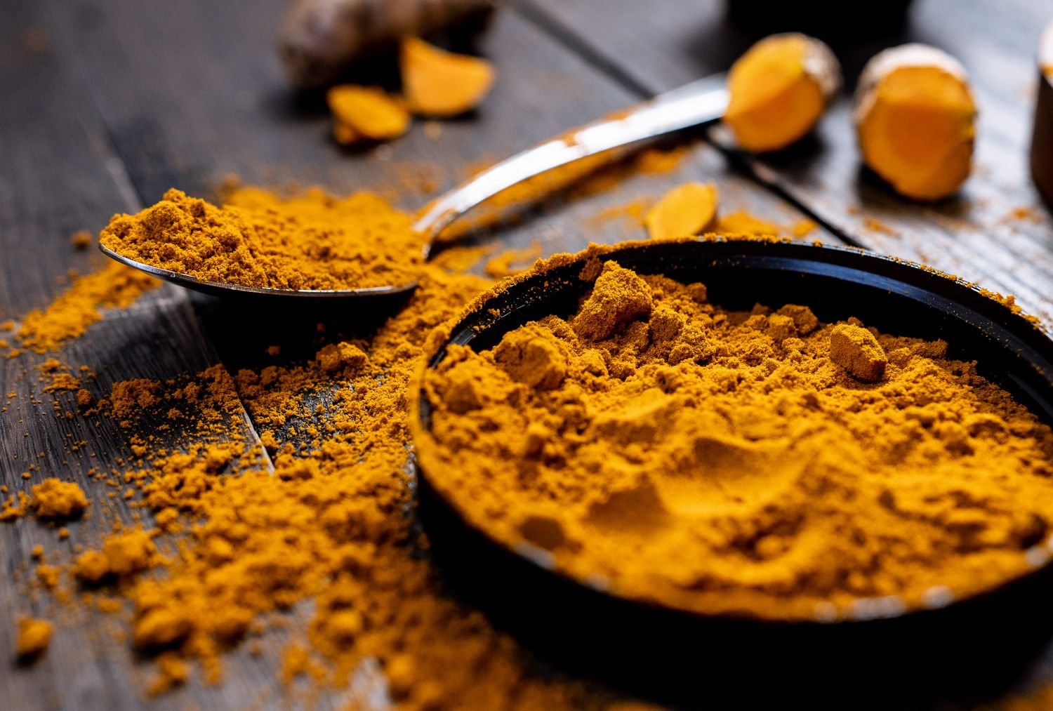 Turmeric powder and fresh turmeric root on a wooden table